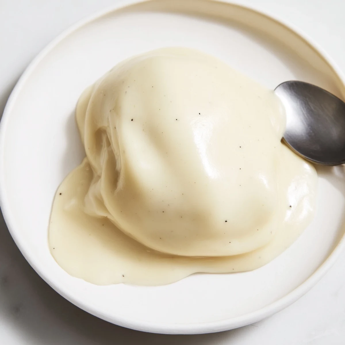 Homemade creamy pastry filling glistening from the bowl, awaiting incorporation into layered cake.