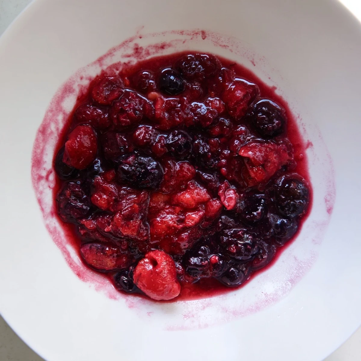 Spoonful of warm berry compote drizzled over fluffy pancakes, a sweet breakfast delight.