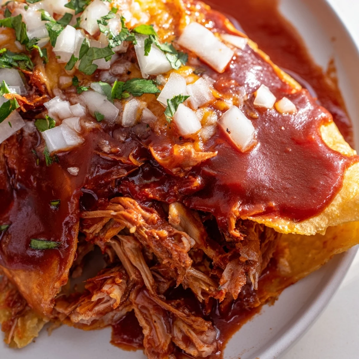 A fork lifts juicy beef from a birria taco, highlighting the deep red, spiced consommé for dipping.