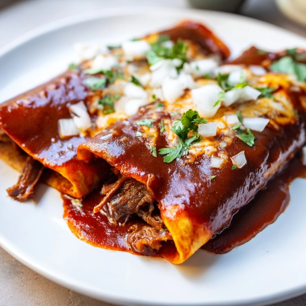A bowl of rich consommé sits beside beef birria tacos, garnished with fresh cilantro and diced onions.