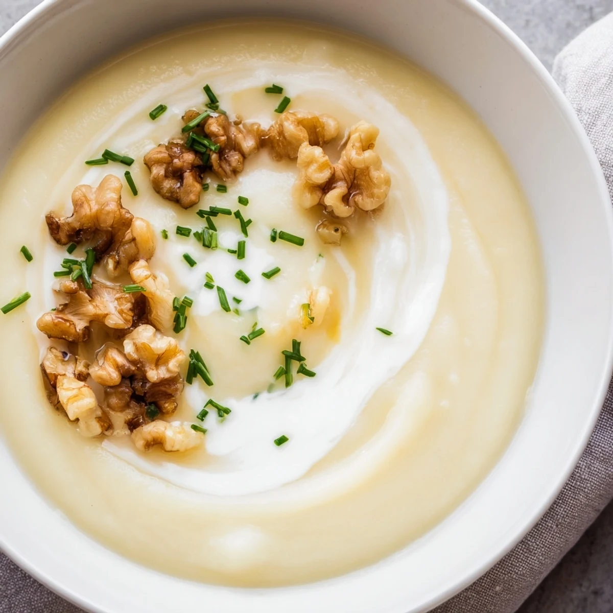 Silky smooth soup in a rustic bowl, topped with toasted walnuts and fresh chives, perfect for cozy dinners.