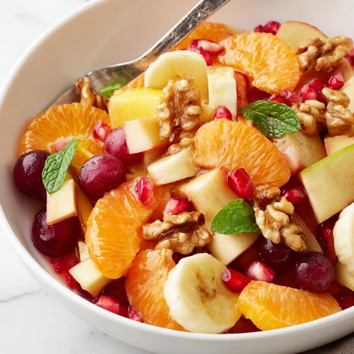 Freshly prepared Winter Fruit Salad with Citrus in a white bowl, showcasing juicy orange and grapefruit segments mixed with diced apples and bright pomegranate seeds.