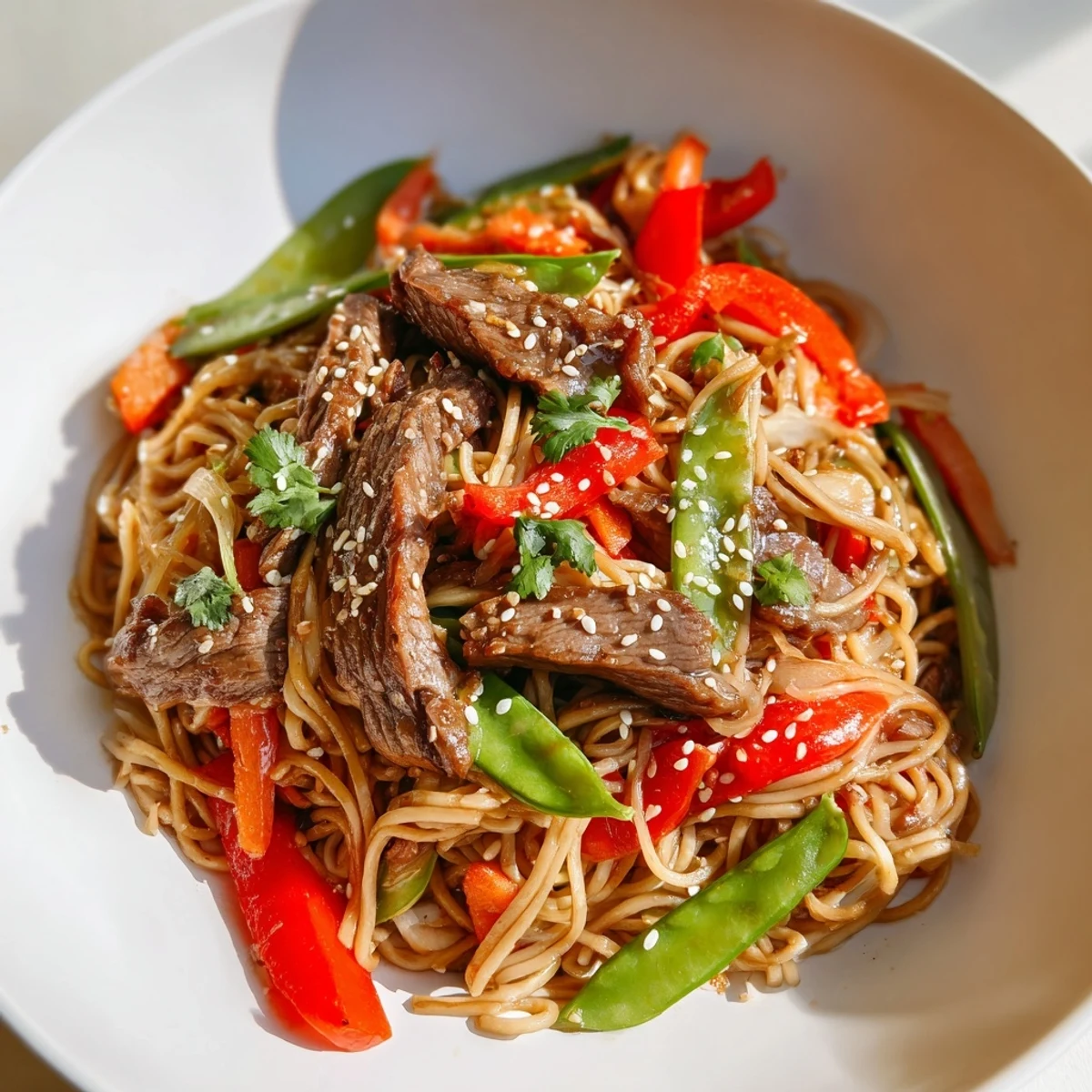Close-up of Spicy Beef Noodles featuring julienned carrots, snap peas, and a glossy, savory sauce.