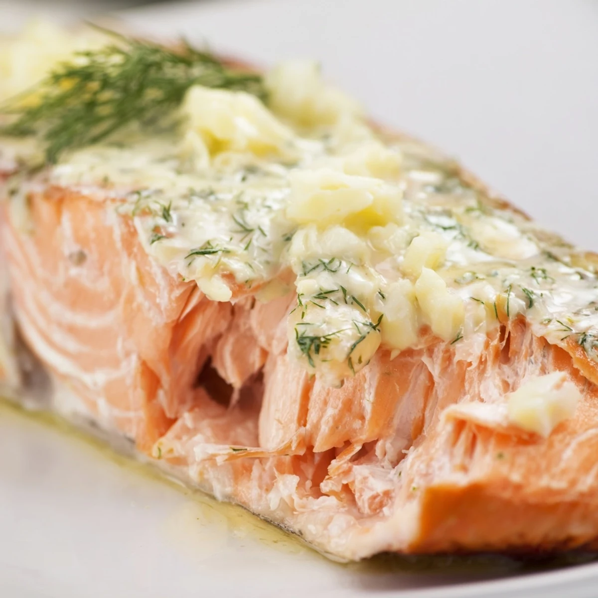 A close-up of tender Baked Salmon with Garlic Butter and Dill Sauce served alongside crisp roasted asparagus. 