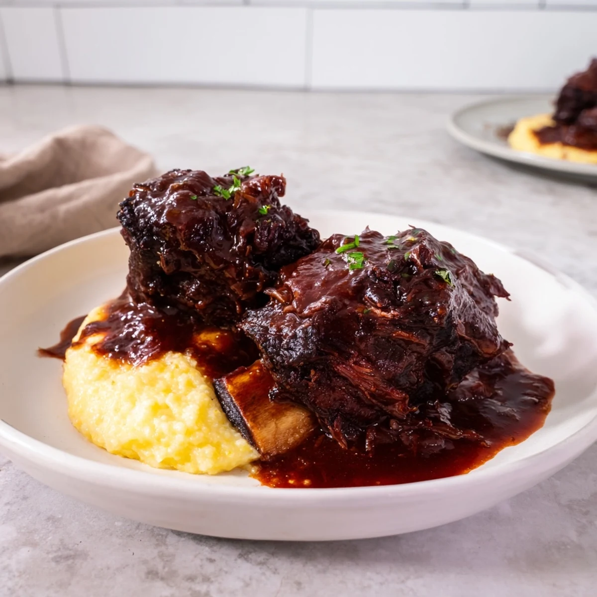 Savory Slow Cooked Beef Short Ribs with Creamy Polenta served with Parmesan and herbs.