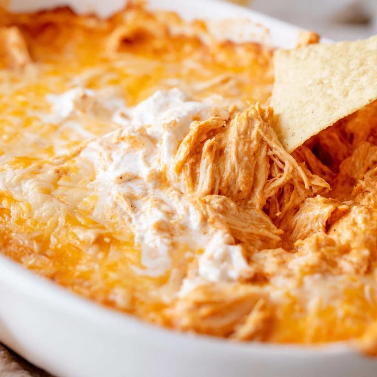 Golden, bubbly Game Day Buffalo Chicken Dip fresh from the oven, served in a rustic dish alongside a generous pile of crunchy tortilla chips ready for scooping.