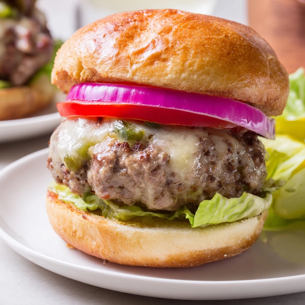 Freshly grilled spicy jalapeño beef sliders topped with melted pepper jack cheese and crisp lettuce on a toasted bun.  