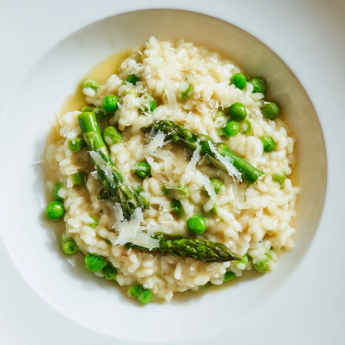 Close-up of creamy asparagus and pea risotto, highlighting tender green veggies and a luxurious, cheesy finish.