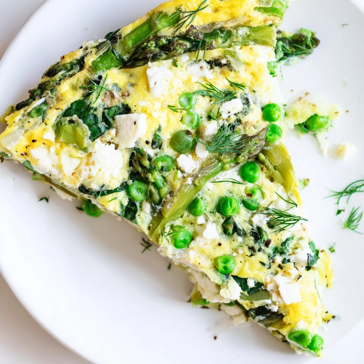 Spring Vegetable Frittata with Goat Cheese and Herbs is baked in a skillet until golden and puffed, filled with tender asparagus, peas, and wilted spinach.