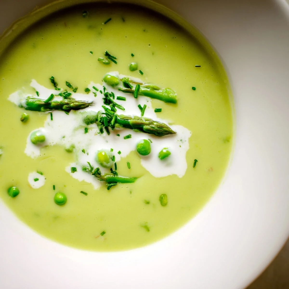 A close-up of velvety roasted asparagus and pea soup with vibrant green hues and seasoning.