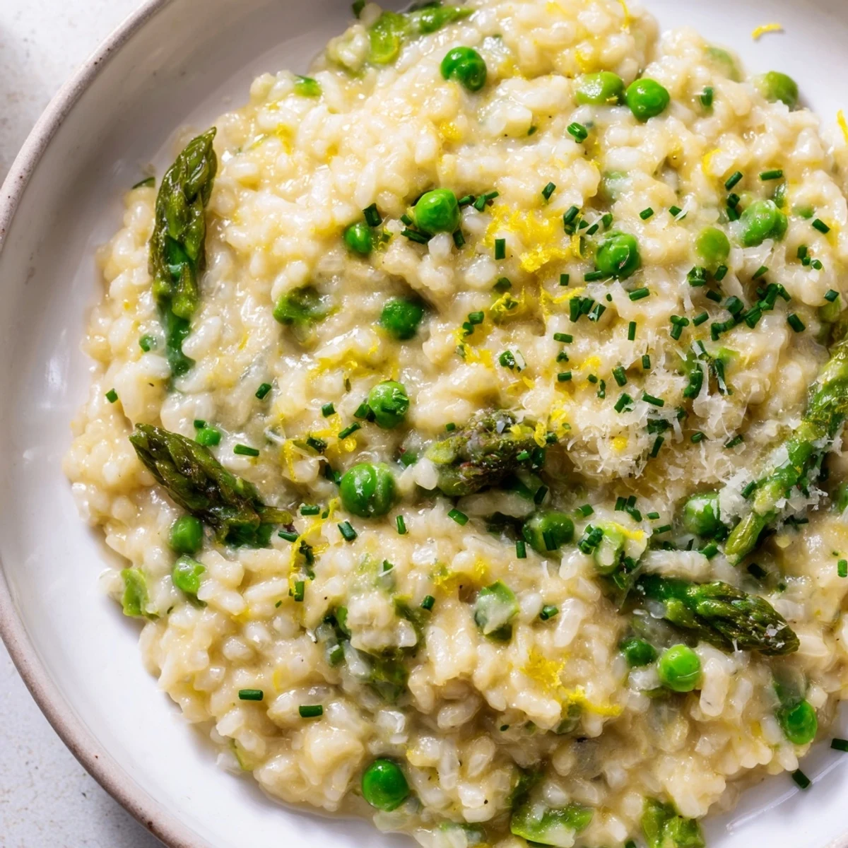 A skillet of Creamy Spring Pea and Asparagus Risotto highlights tender green vegetables, Parmesan, and rich buttery texture.