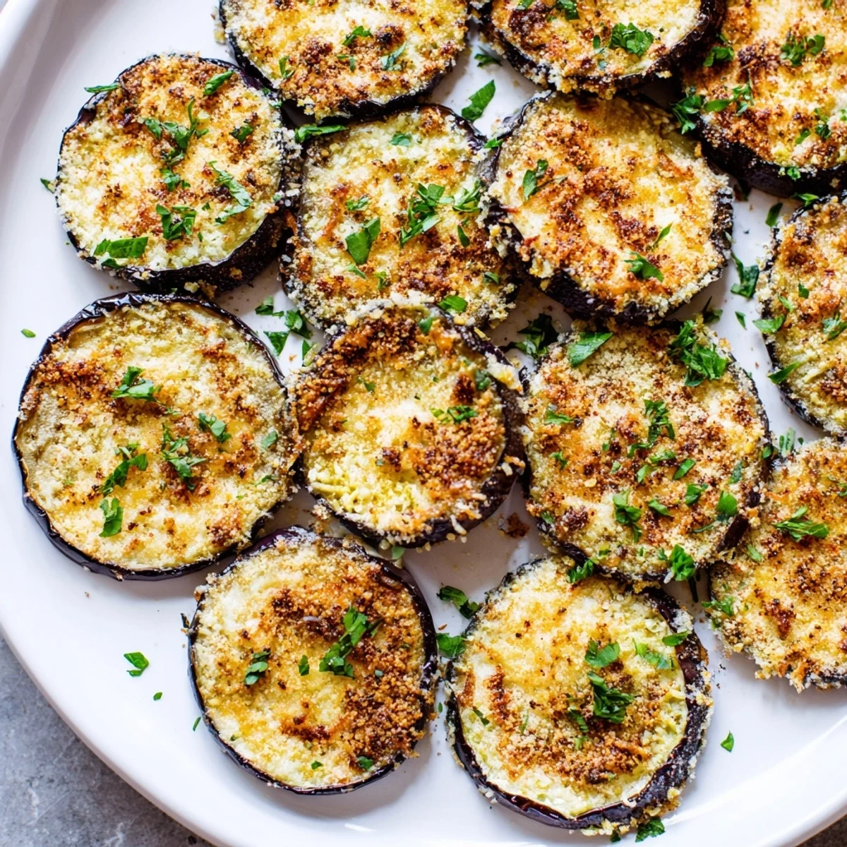 Close-up of Mediterranean Roasted Eggplant & Parmesan Crisps showing bubbly, golden cheese and tender eggplant on a rustic wooden serving board.