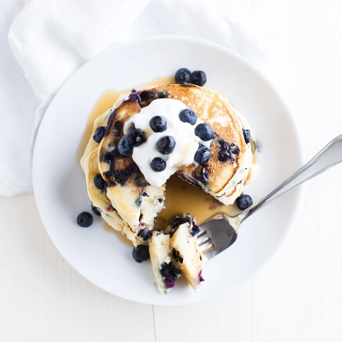 Golden Greek Yogurt Blueberry Pancakes sizzling on a griddle, topped with fresh berries and a drizzle of maple syrup.