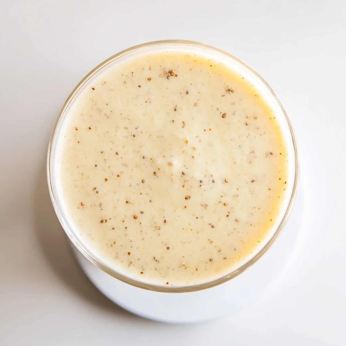 Creamy Greek yogurt banana smoothie poured into a tall glass topped with fresh banana slices