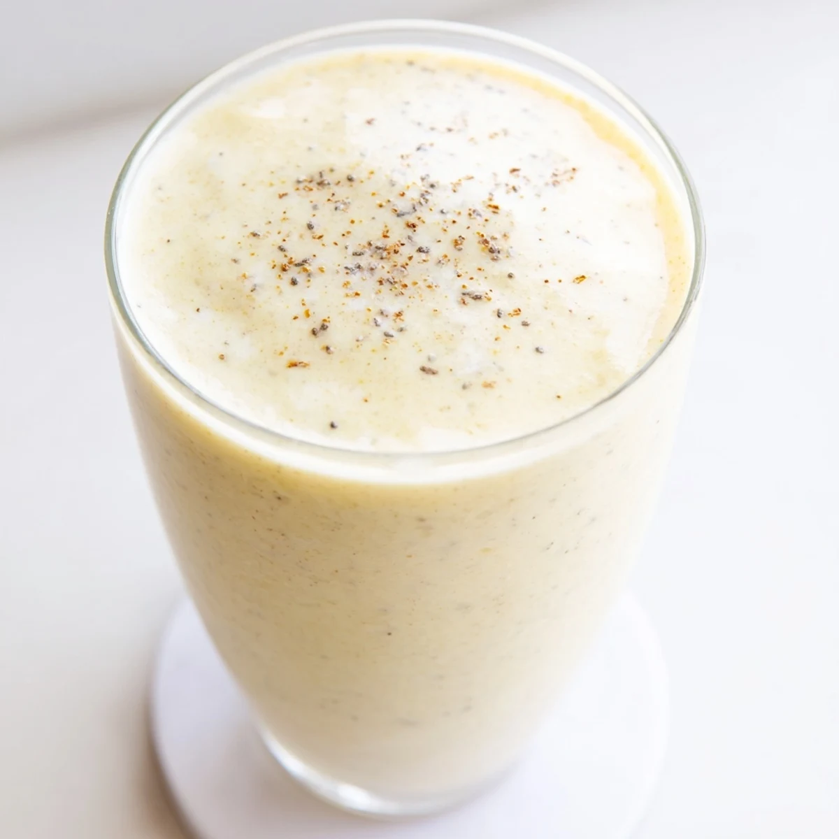 Protein-packed Greek yogurt banana smoothie in a clear glass showing its smooth pale yellow texture