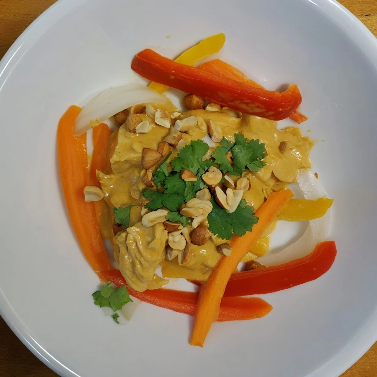 Creamy peanut sauce coats tender chicken thighs with bell peppers and fresh cilantro garnish