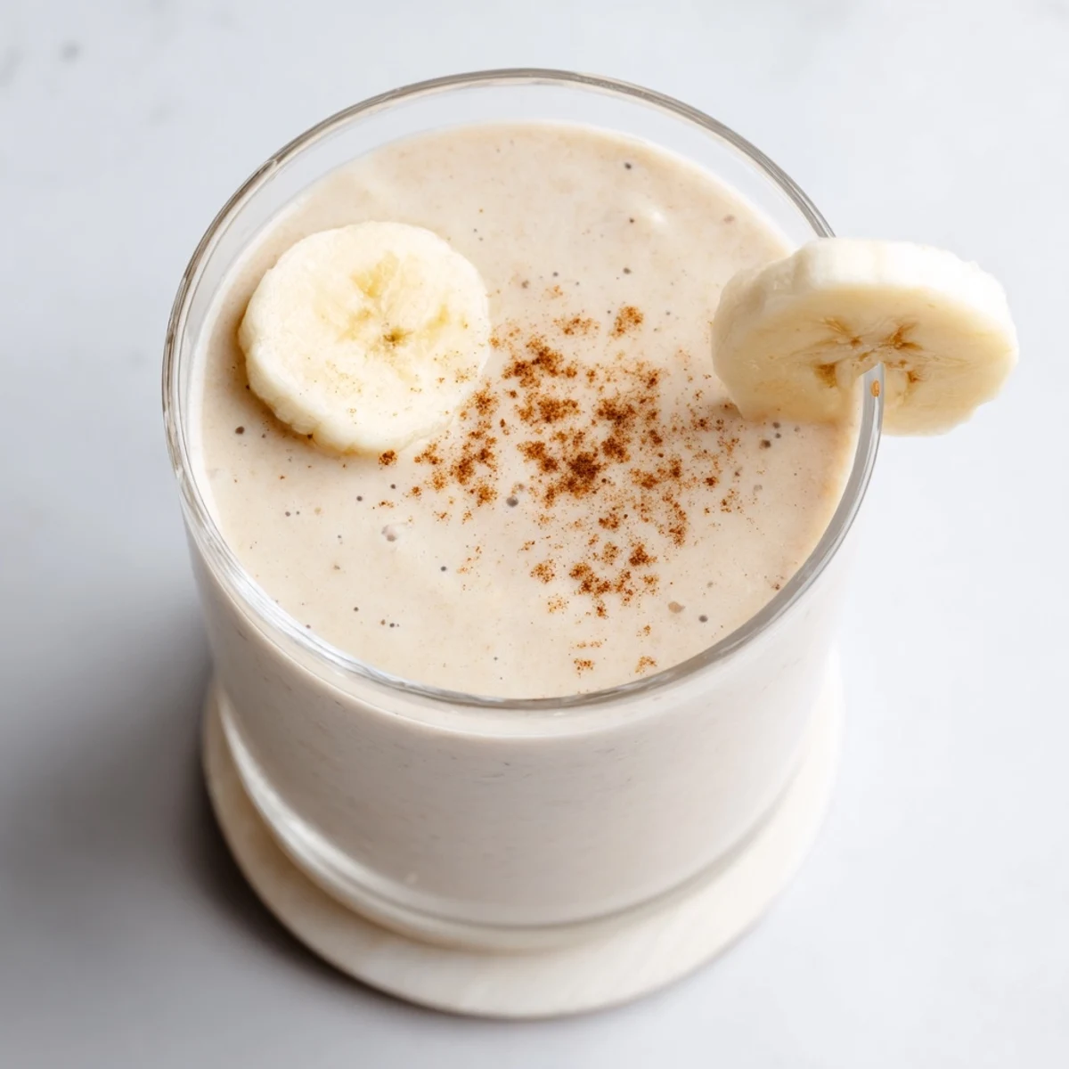Golden Greek yogurt banana smoothie blending frozen bananas and vanilla in chilled glass