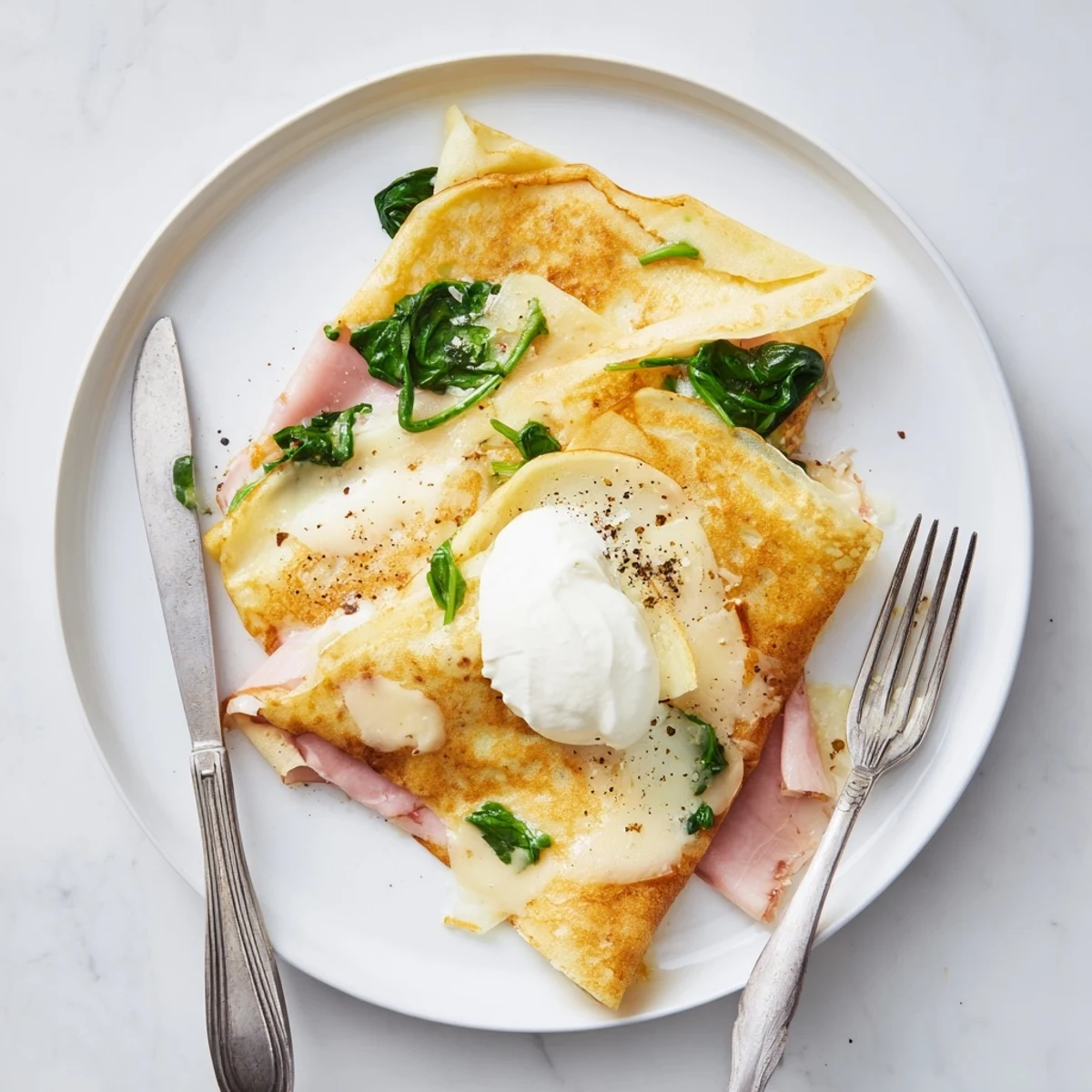 French-style savory crepes layered with ham, baby spinach, and cream, served warm from the oven.