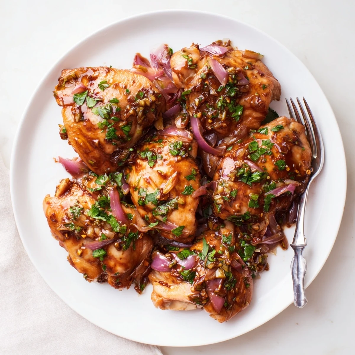 Tender chicken thighs swimming in tangy balsamic glaze alongside caramelized red onion slices