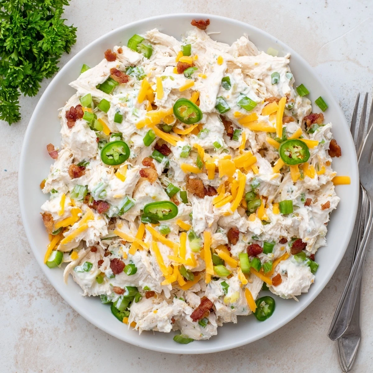 Golden brown bacon crumbles and diced jalapeños sprinkled over this zesty low carb jalapeño popper cottage cheese chicken salad in a rustic serving dish