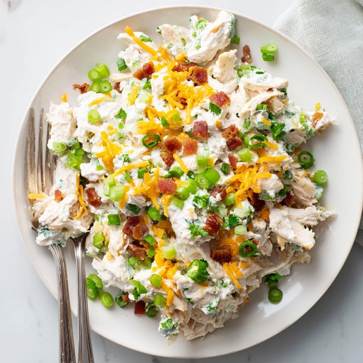 Close-up of low carb jalapeño popper cottage cheese chicken salad showing creamy texture with shredded cheddar and fresh parsley garnish