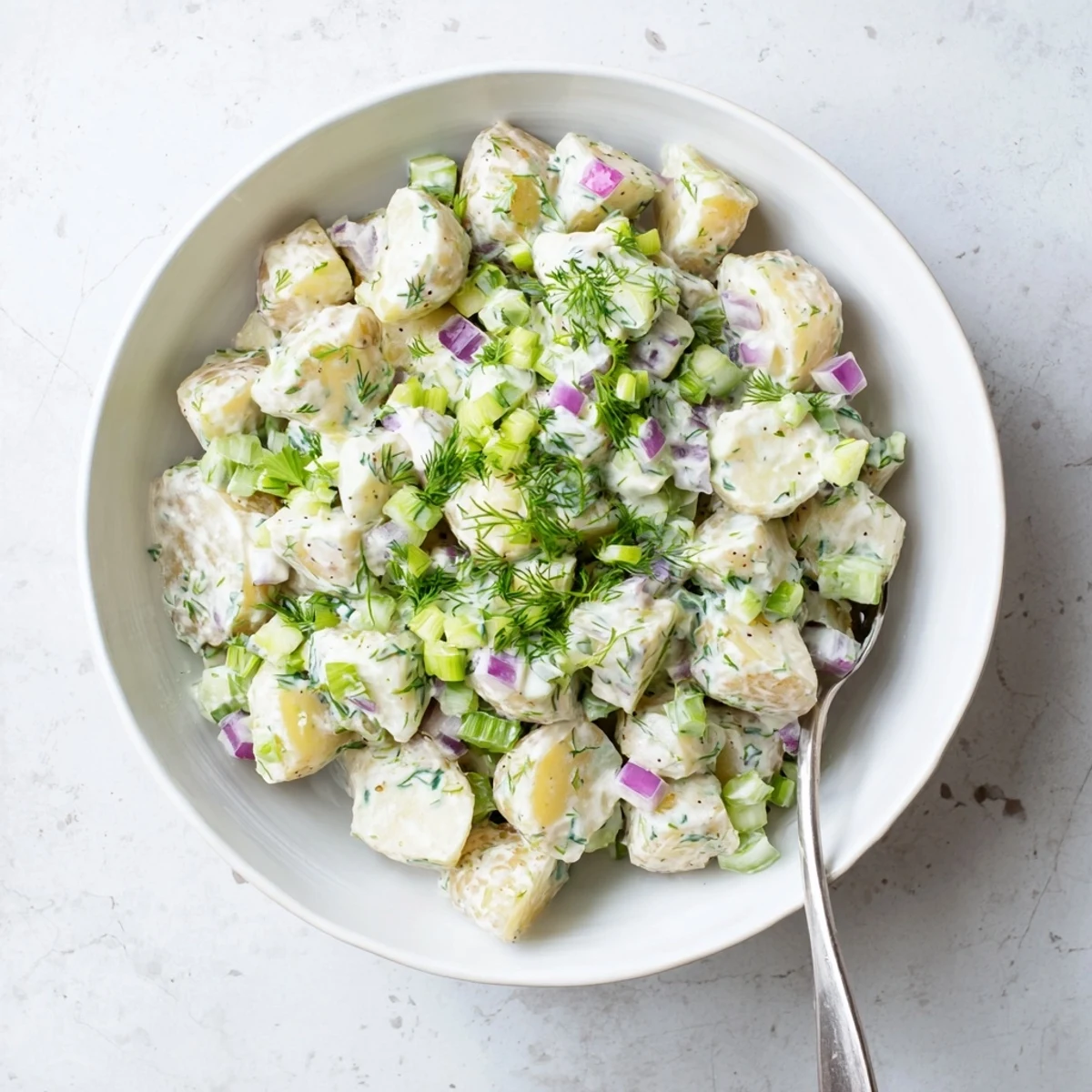 Greek yogurt potato salad topped with chopped chives and fresh dill, served chilled for summer barbecues and picnics