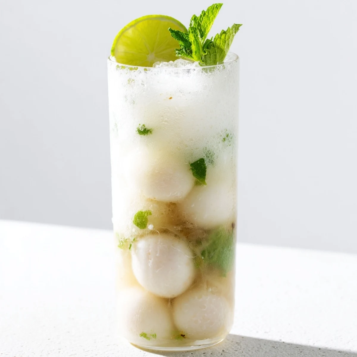 Tropical coconut lychee iced beverage served over ice with whole lychee fruit floating on top
