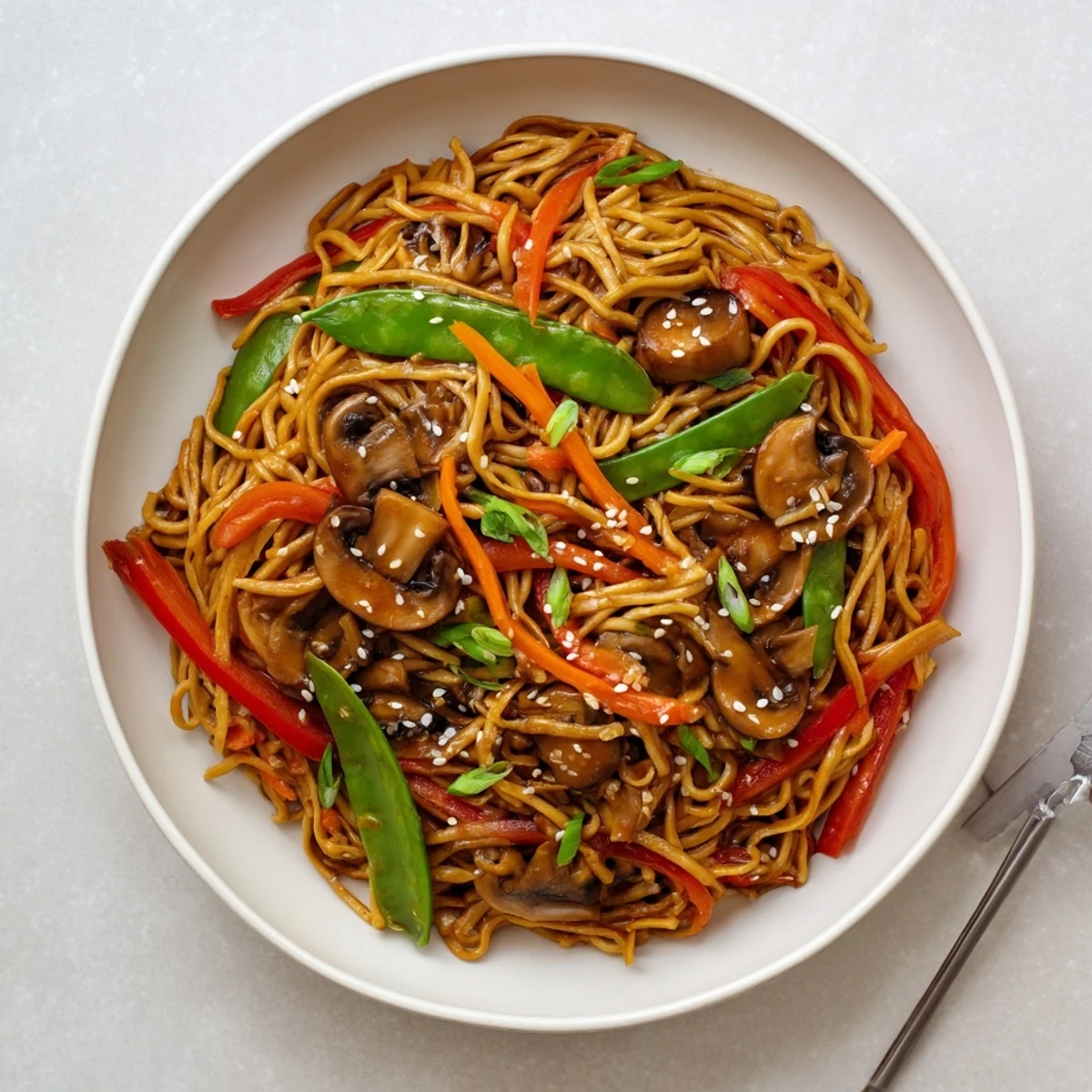 Golden garlic mushroom chow mein noodles tossed with colorful crisp vegetables in a dark savory sauce