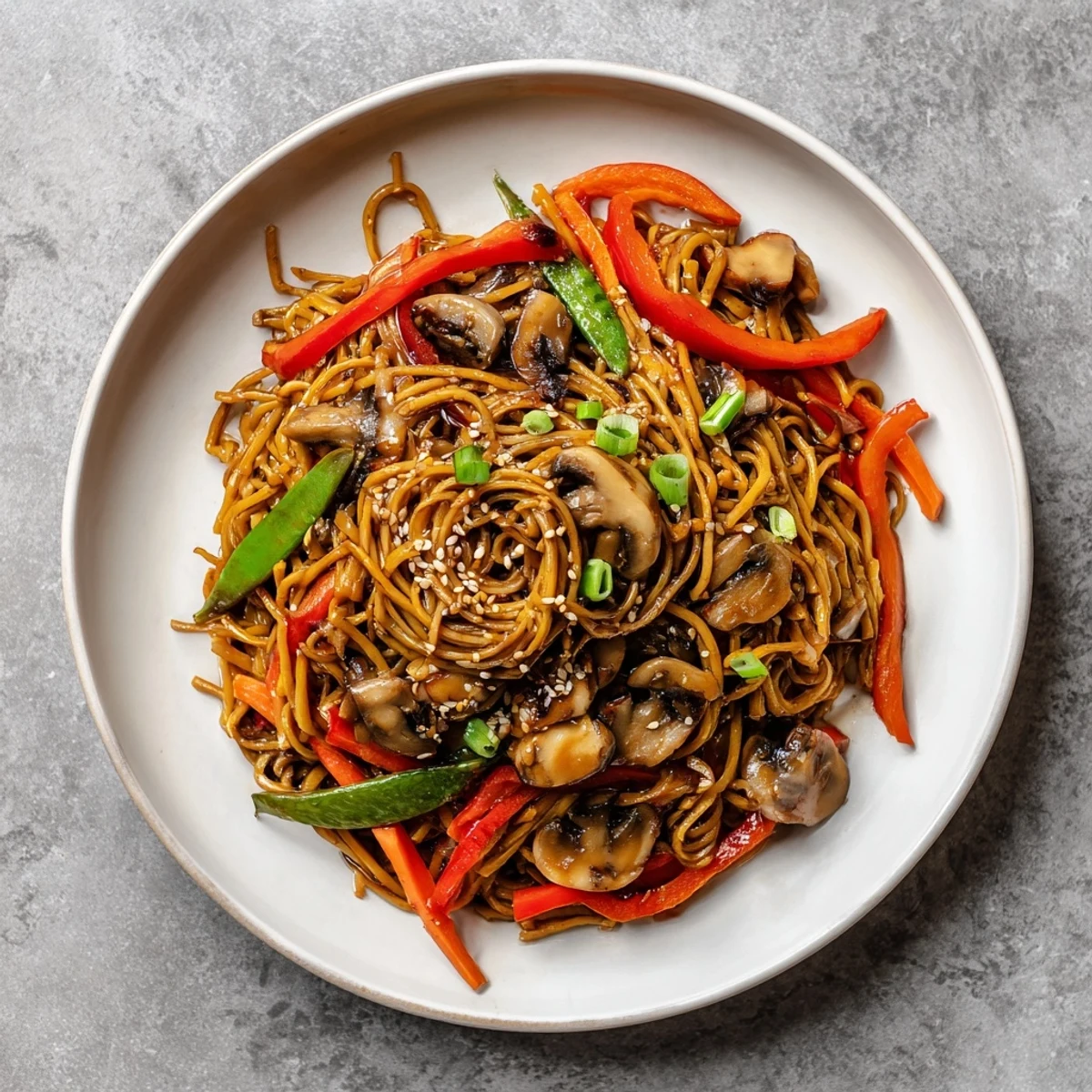 Wok-fried garlic mushroom chow mein featuring tender egg noodles with sliced bell peppers and snap peas