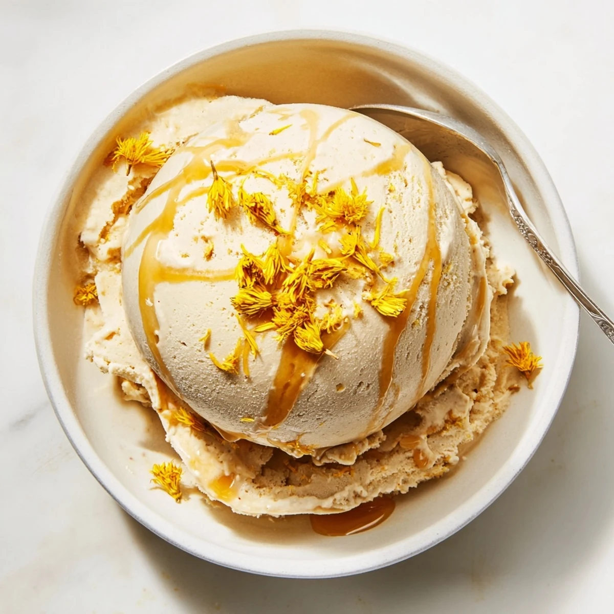 Golden scoops of floral dandelion honey ice cream garnished with fresh yellow dandelion petals