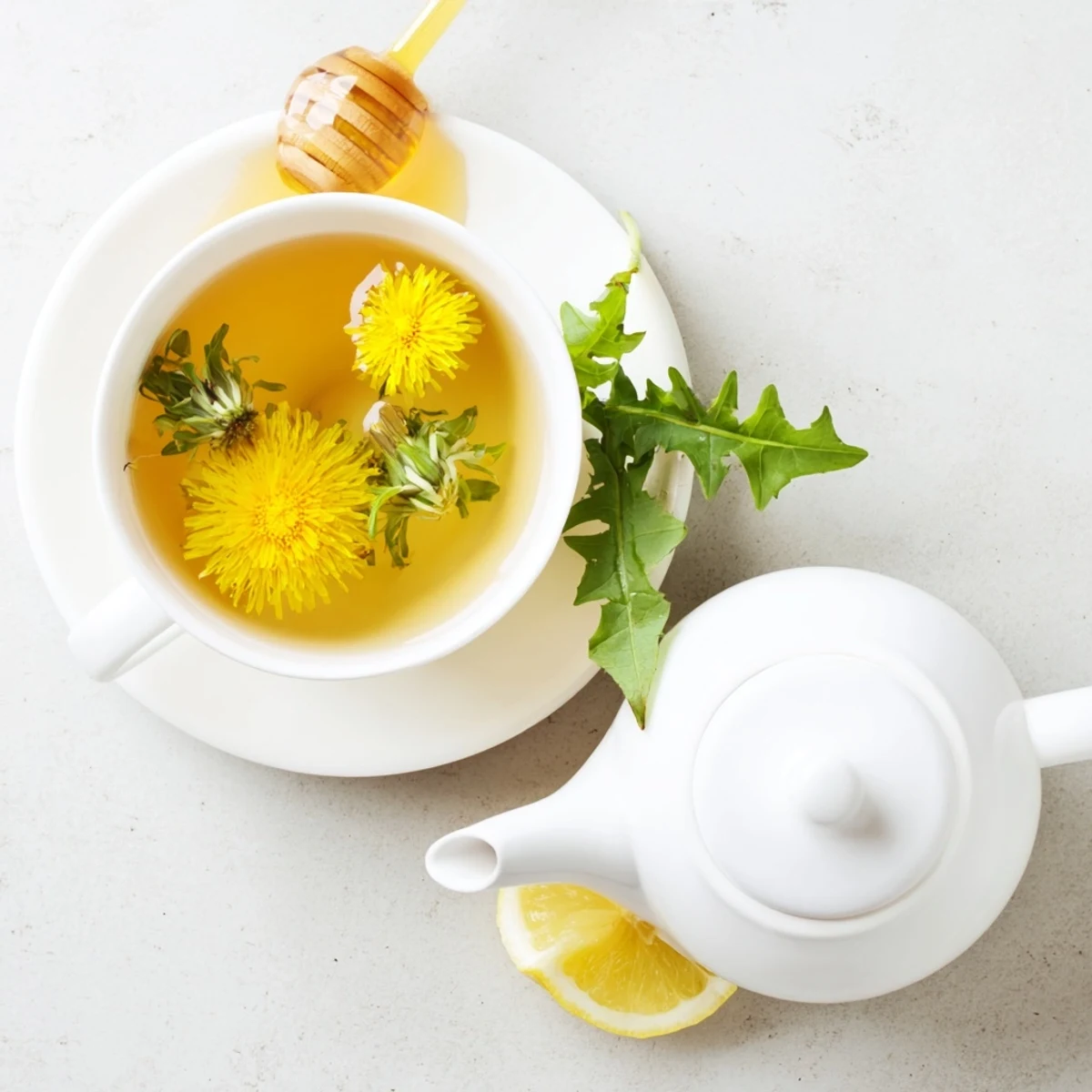 Warm dandelion tea pouring into glass cups beside fresh harvested yellow flowers