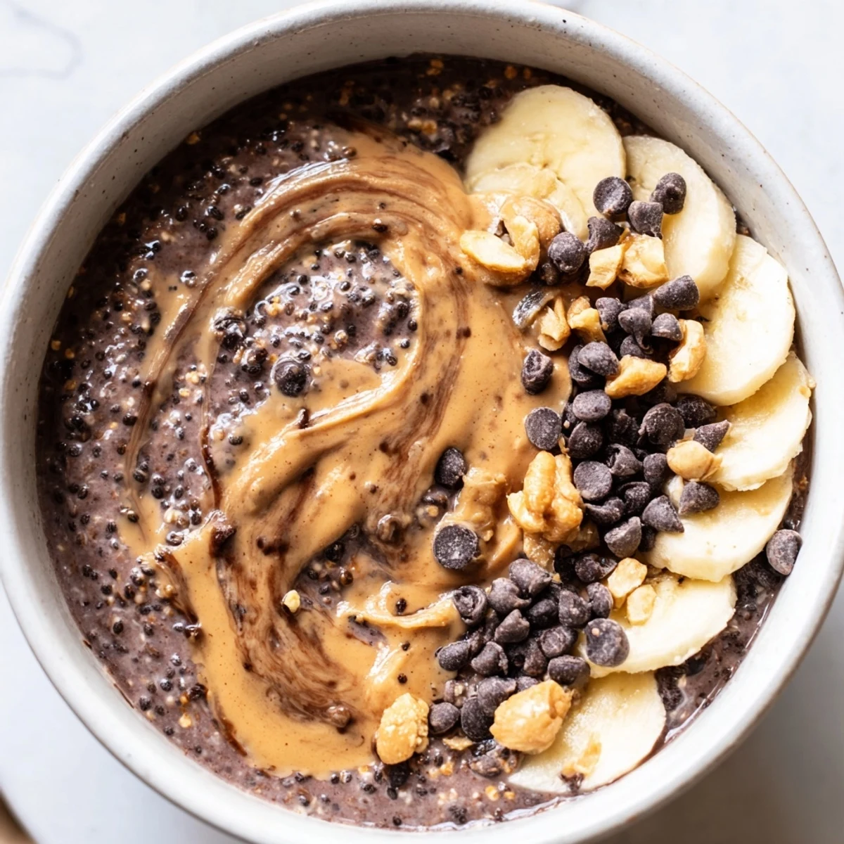 Thick chocolate peanut butter overnight oats swirled with peanut butter and fresh banana slices