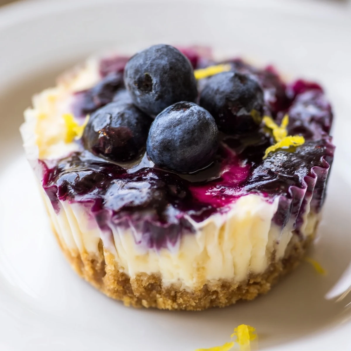 Chilled Mini Lemon Blueberry Cheesecakes garnished with fresh berries and bright lemon zest
