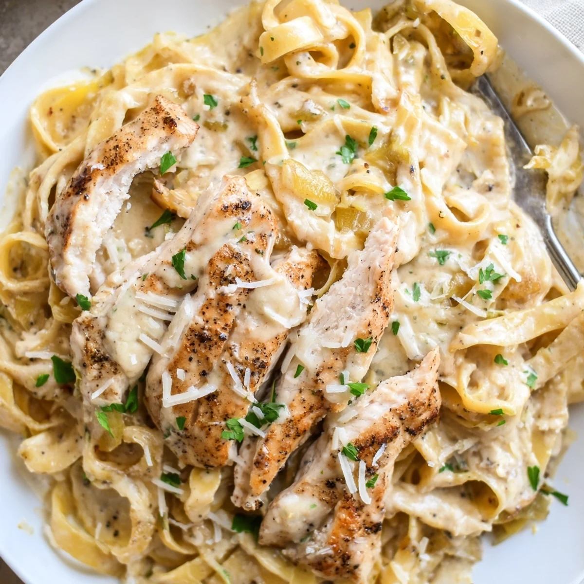 A steaming bowl of Creamy Garlic Chicken Pasta topped with Parmesan.