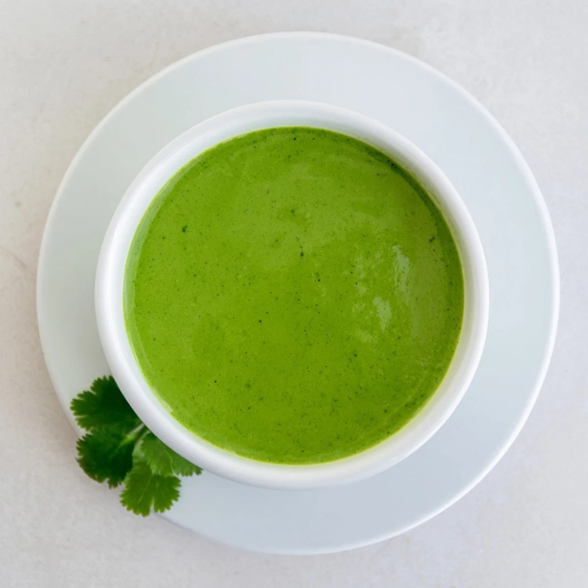 Creamy Peruvian green sauce aji verde in small white bowl garnished with fresh cilantro