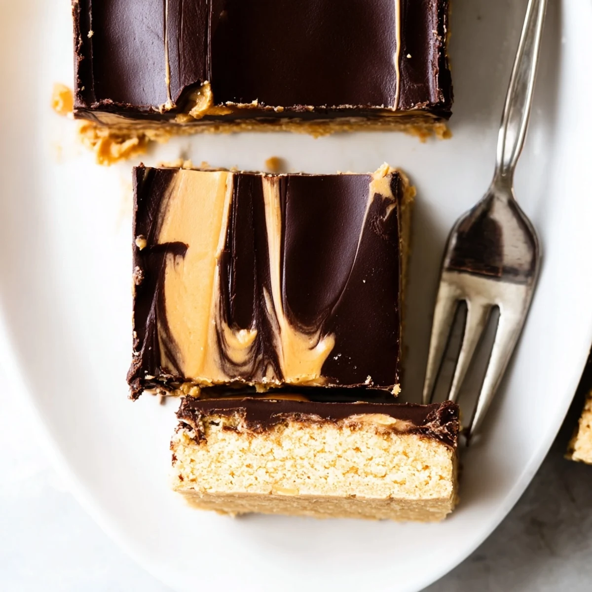 Golden peanut butter bars sliced into squares featuring glossy chocolate topping and crumbly graham base