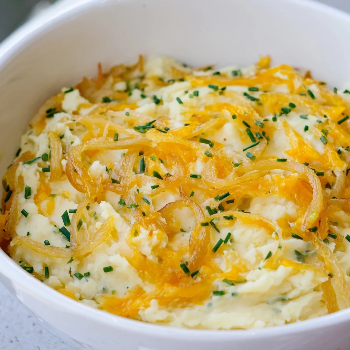 Creamy cheesy onion mashed potato casserole served in a rustic baking dish with caramelized onion topping
