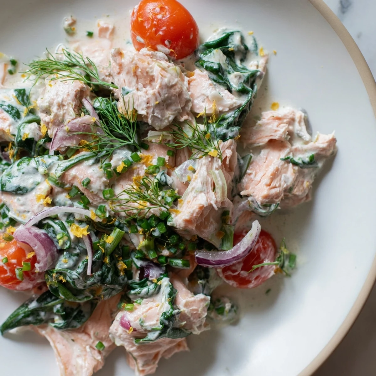 Creamy leftover salmon recipe served in a skillet with bright cherry tomatoes and fresh dill