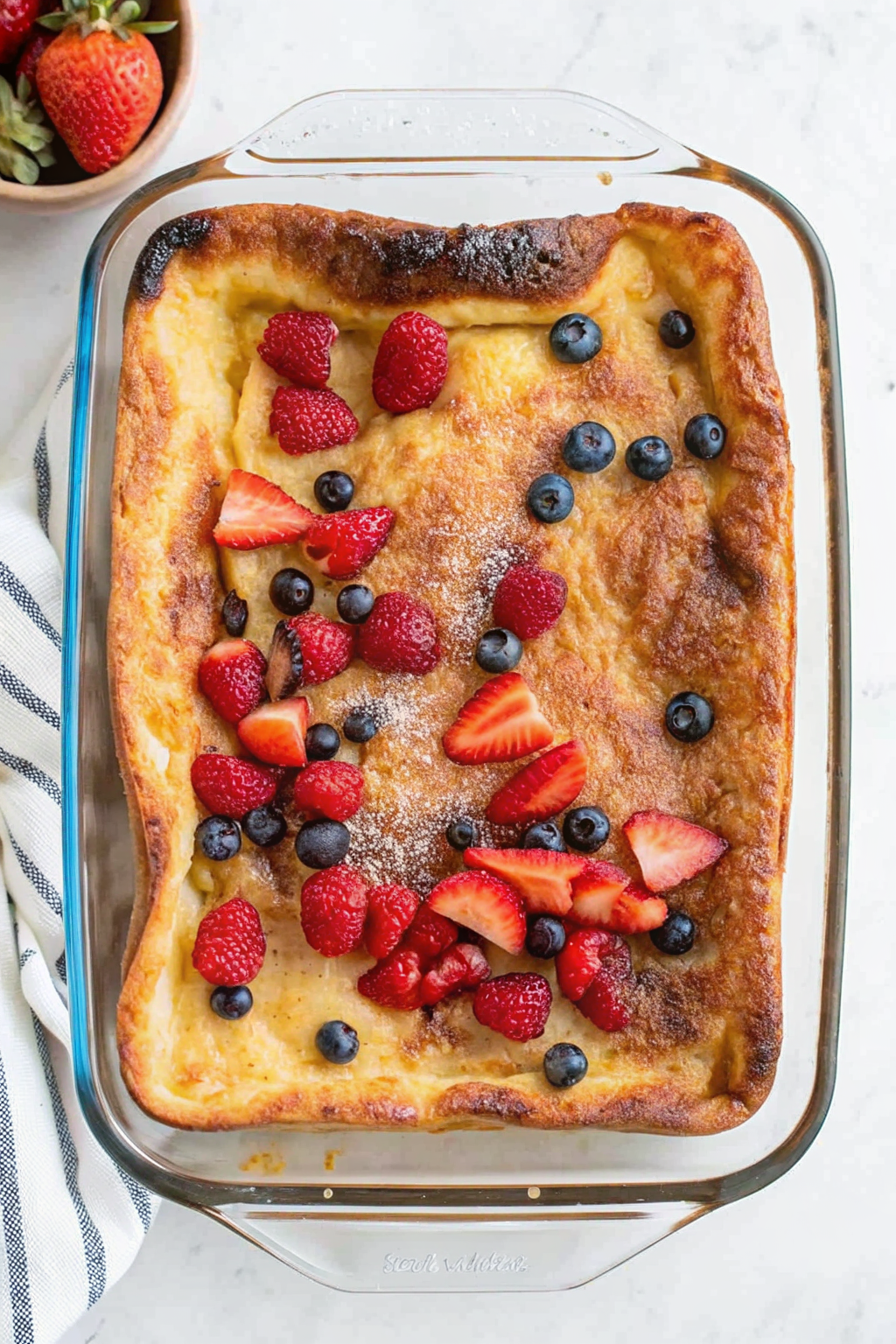 Gluten free Dutch baby pancake with berries in cast iron skillet